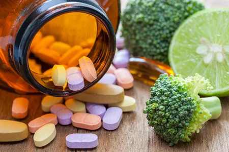 medicine bottle with tablets inside next to broccoli to represent weightloss pills