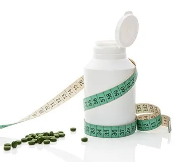 White medicine bottle wrapped in a tape measure next to pills