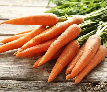 Bunch of carrots on a wooden table with a load of vitamin c
