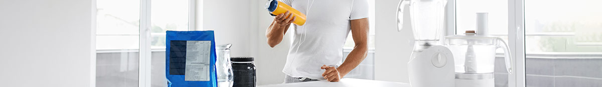 man holding protein shake bottle next to amino acid powders and blenders man holding protein shake bottle next to amino acid powders and blenders