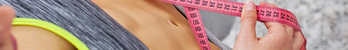 A woman measuring her loss of belly fat after taking appetite suppressants