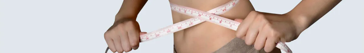 A woman measuring her belly fat loss with a measuring tape post taking weight loss supplements