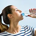 woman drinking water from a bottle to show that she is not dehydrated