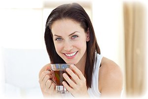 Woman Drinking Green Tea while smiling to the camera
