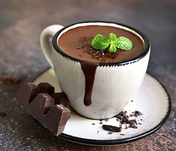 mug filled with hot chocolate with dark chocolate next to it