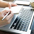 image of woman of a laptop making notes on a notebook