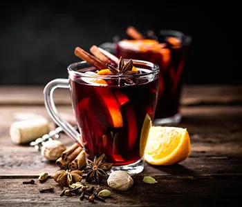 Two glasses of mulled wine on a wooden table with cinnamon