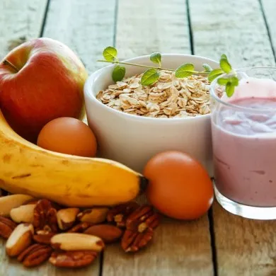 bowl of oats with a glass of yogurt, fruits and nuts