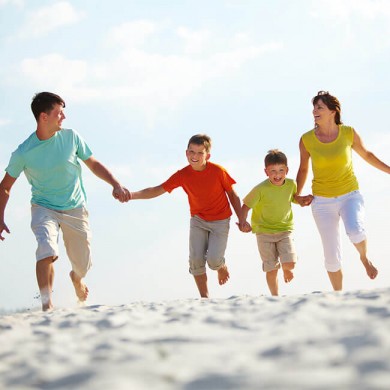family consisting of mum dad and two young boys running on a beach to represent healthy happy lifestyle