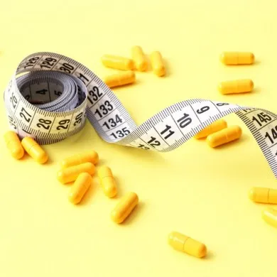 Tape measure next to Yellow capsules on a yellow background