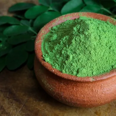 moringa podwer in a clay pot next to moringa leaves