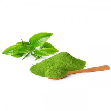 a pile of moringa powder with a spoonfull of moringa powder next to some moringa leaves