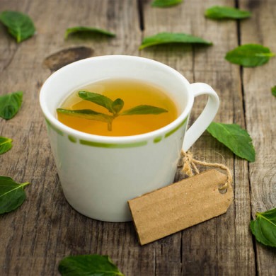 image of a cup of green tea surrounded by green tea leaves