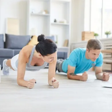 man and woman doing a plank in a living room to show exercises you can do at home