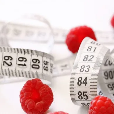a couple of raspberries laying next to a measuring tape