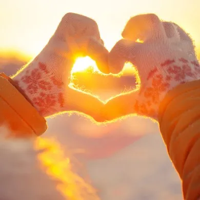 womans hands with gloves showing heart with fingers in cold weather