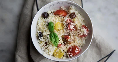 Bowl Of Mediterranean Cauliflower Couscous Recipe With Cherry Tomatoes and Olives.