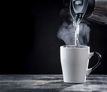 a mug being filled with hot water from a boiling kettle