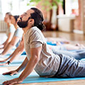 man doing a yoga stretch on a yoga mat in a yoga sudio